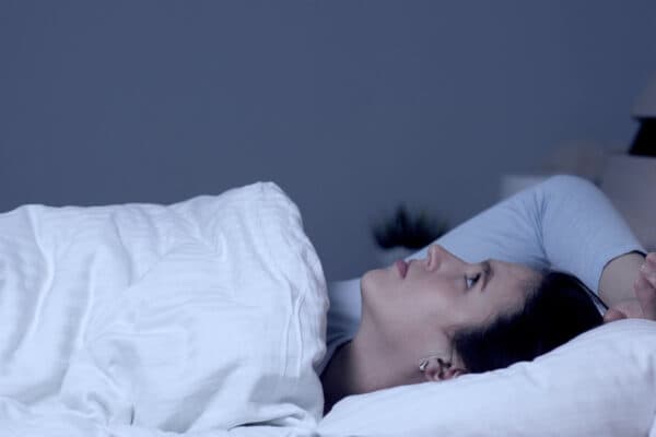 woman lies in bed unable to sleep